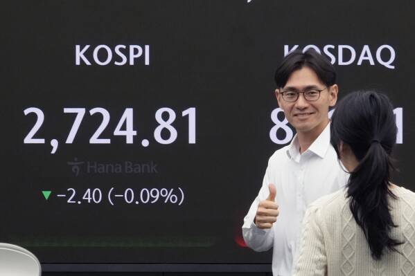 2024年5月14日，星期二，韩国首尔，韩国央行韩亚银行（KEB Hana Bank）总部的外汇交易室，一名外汇交易员在显示韩国综合股价指数（KOSPI）的屏幕附近猛击。亚洲股市周二涨跌互现，美国股指走势喜忧参半。（美联社照片/Ahn Young-joon）