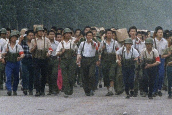 In this June 6, 1989, photo, Chinese soldiers marching away from Tiananmen point out an an Associated Press reporter taking photos, which was against the regulations of martial law that had been declared May 20 and later gave chase, firing twice before the reporter escaped near the International Hotel in Beijing. The Chinese army had fought its way into Tiananmen Square the night of June 3-4 to reclaim the square from student-led demonstrators who had been protesting for democratic reforms for three weeks. (AP Photo/Terril Jones)