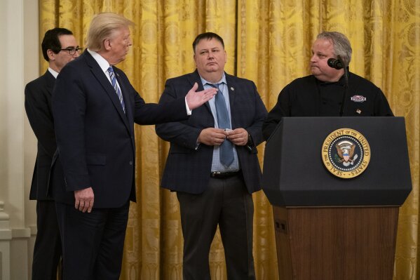 President Donald Trump talks with Ford's Fish Shack employee Mark Underwood during an event about the Paycheck Protection Program used to support small businesses during the coronavirus outbreak, in the East Room of the White House, Tuesday, April 28, 2020, in Washington, as Treasury Secretary Steven Mnuchin, and Ford's Fish Shack founder Tony Stafford, and Underwood watch. (AP Photo/Evan Vucci)