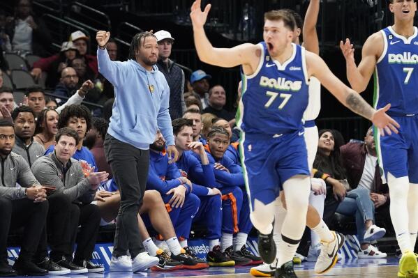 Wearing streets clothes, New York Knicks' Jalen Brunson, left, reacts to a call with Dallas Mavericks' Luka Doncic (77) and Dwight Powell (7) during the third quarter of an NBA basketball game in Dallas, Tuesday, Dec. 27, 2022. (AP Photo/LM Otero)