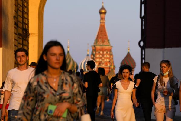 People, most of them without face masks, walk at Red Square during sunset in Moscow, Russia, Thursday, June 24, 2021. An ambitious plan of vaccinating 30 million Russians by mid-June against the coronavirus has fallen short by a third, and the country has started to see a surge in daily new infections. (AP Photo/Alexander Zemlianichenko)