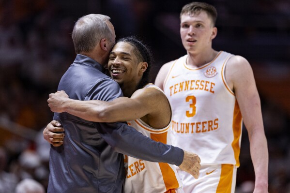 Tennessee head coach Rick Barnes gets a hug from guard Zakai Zeigler as guard Dalton Knecht (3) watches during the second half of an NCAA college basketball game against Texas A&M Saturday, Feb. 24, 2024, in Knoxville, Tenn. (AP Photo/Wade Payne)