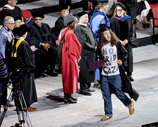 A graduate displays a message on his shirt, 