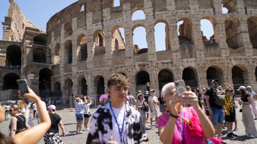Visitors take photos of the Ancient Colosseum, in Rome, Tuesday, June 27, 2023. Italy's culture and tourism ministers Gennaro Sangiuliano vowed to find and punish a tourist who was filmed carving his name and his girlfriend's name in the wall of the Colosseum, a crime that in the past has resulted in hefty fines. Video of the incident went viral on social media, at a time when Romans have already been complaining about hordes of tourists returning to peak season travel this year. (AP Photo/Andrew Medichini)