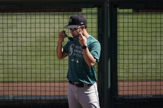 Seattle Mariners starting pitcher Yusei Kikuchi puts on his mask in the bullpen before the team's baseball game against the Los Angeles Angels in Anaheim, Calif., Thursday, June 3, 2021. (AP Photo/Jae C. Hong)