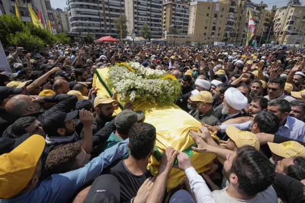 People carry the coffin of Hezbollah senior commander Taleb Sami Abdullah, 55, known within Hezbollah as Hajj Abu Taleb, who was killed late Tusday by an Israeli strike in south Lebanon, during his funeral procession in the southern suburbs of Beirut, Lebanon, Wednesday, June 12, 2024. Hezbollah fired a massive barrage of rockets into northern Israel on Wednesday to avenge the killing of the top commander in the Lebanese militant group as the fate of an internationally-backed plan for a cease-fire in Gaza hung in the balance. (AP Photo/Bilal Hussein)