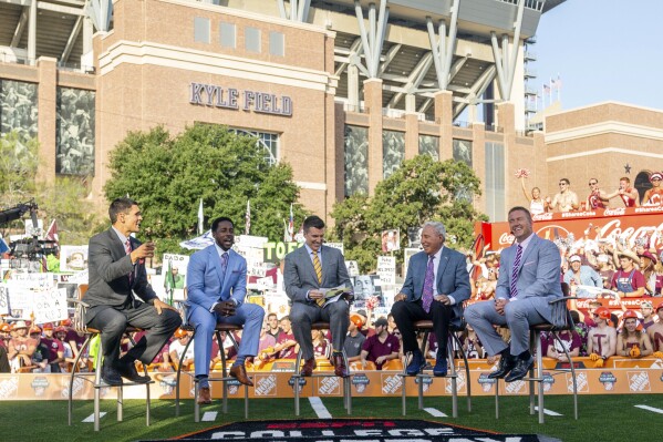 FILE - The ESPN "College Game Day" crew sits on set in front of Kyle Field in College Station, Texas, before an NCAA college football game between Clemson and Texas A&M, Sept. 8, 2018. “College GameDay” has continued its reign as the preeminent pregame show leading into Saturday afternoon kickoffs. But the ESPN franchise goes into its 37th year with the most changes it has had going into a season as well as facing competition from Fox and its upstart “Big Noon Kickoff.” (AP Photo/Sam Craft, File)