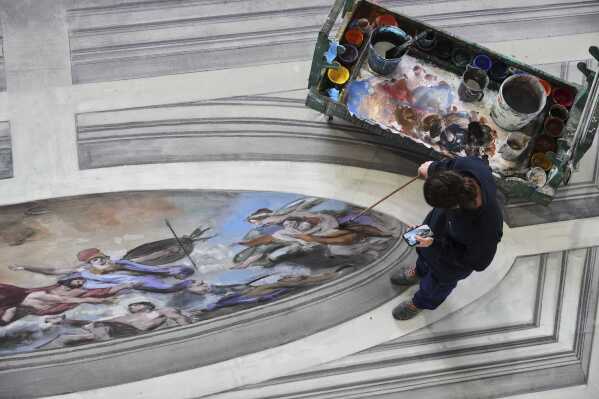 A set designer works on a stage canvas in the "Teatro dell' Opera" opera house warehouse, in Rome, Thursday, April 10, 2025. (AP Photo/Andrew Medichini)