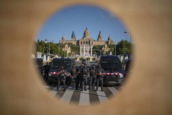 Police officers are seen through the hole of a guillotine which was brought to a protest against the visit of Spain's King Felipe VI to Barcelona, Spain, Sunday, June 27, 2021. Supporters of independence for Catalonia have protested against a visit to its regional capital Barcelona by Spain's King Felipe VI, who is a symbol of rule from Madrid. The king is in Barcelona to help mark the opening of a major international wireless trade fair. (AP Photo/Joan Mateu)