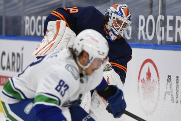 Edmonton Oilers goalie Mikko Koskinen (19) and Vancouver Canucks' Jay Beagle (83) work for the puck during the third period of an NHL hockey game Wednesday, Jan. 13, 2021, in Edmonton, Alberta. (Dale MacMillan/The Canadian Press via AP)