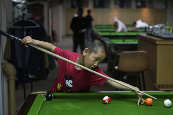 Li Zelei, 8 years old, practice on a pool table at the Beijing Xinrui Billiard Academy in Beijing, Tuesday, May 6, 2025. (AP Photo/Ng Han Guan)