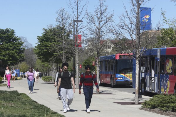 Students walk down Jayhawk Boulevard, the main street through the main University of Kansas campus, Friday, April 12, 2024, in Lawrence, Kan. The Kansas Board of Regents, which oversees higher education, has drafted a new policy against requiring diversity, equity and inclusion statements on applications for students, job seekers and staff promotions. (AP Photo/John Hanna)