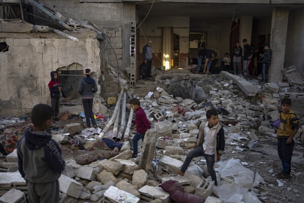Palestinians look at the destruction after an Israeli strike in Rafah, southern Gaza Strip, Friday, Dec. 29, 2023. (AP Photo/Fatima Shbair)