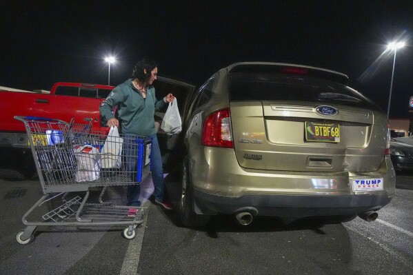 Macey Lane loads groceries she purchased at a store where measles exposures were reported in Hobbs, N.M., Monday, Feb. 24, 2025. (AP Photo/Julio Cortez)