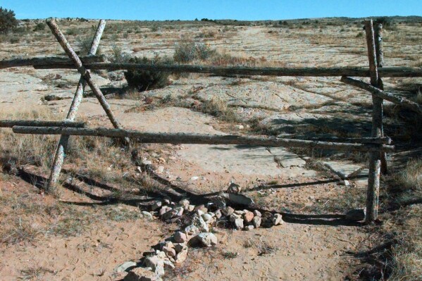 FILE - A cross made of stones rests below the fence in Laramie, Wyo., on Oct. 9, 1999, where a year earlier, University of Wyoming student Matthew Shepard was tied and pistol whipped into a coma. He later died. The Tectonic Theater Project is marking the anniversary by gathering the original cast and creators of "The Laramie Project," and some of the people represented in the piece for a staged reading and conversation as part of the 2023 Shepard Symposium at the University of Wyoming. (AP Photo/Ed Andrieski, File)