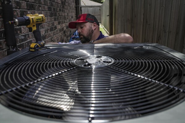 FILE - Ed Newby, owner of All Star A/C and Heating, works on an air conditioning unit on June 26, 2023, in Houston. The Environmental Protection Agency is enforcing stricter limits on hydrofluorocarbons, highly potent greenhouse gases used in refrigerators and air conditioners. A rule announced Tuesday, July 11, would impose a 40% reduction in HFCs below historic levels by 2028, part of a global phaseout of HFCs designed to slow global warming. (Raquel Natalicchio/Houston Chronicle via AP, File)