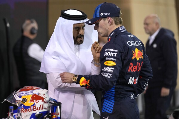 El piloto holandés de Red Bull Max Verstappen (centro) que ganó la clasificación conversa con el presidente de la FIA Mohammed Ben Sulayem, luego del clasificatorio de cara al Gran Premio de Baréin, en el circuito de Sakhir, Baréin, el viernes 1 de marzo de 2024. (AP Foto/Darko Bandic)