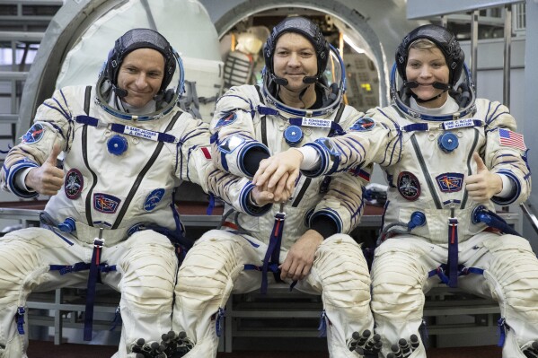 FILE - From left: CSA astronaut David Saint Jacques, Russian cosmonaut Оleg Kononenko and U.S. astronaut Anne McClain pose for a photo before their final preflight practical examination in a mock-up of a Soyuz space craft at Russian Space Training Center in Star City, outside Moscow, Russia, Wednesday, Nov. 14, 2018. The Russian space agency says one of its cosmonauts has broken the world record for the most time spent in space. Oleg Kononenko, who's 59 has made five journeys to the International Space Station, dating back to 2008. (AP Photo/Pavel Golovkin, File)