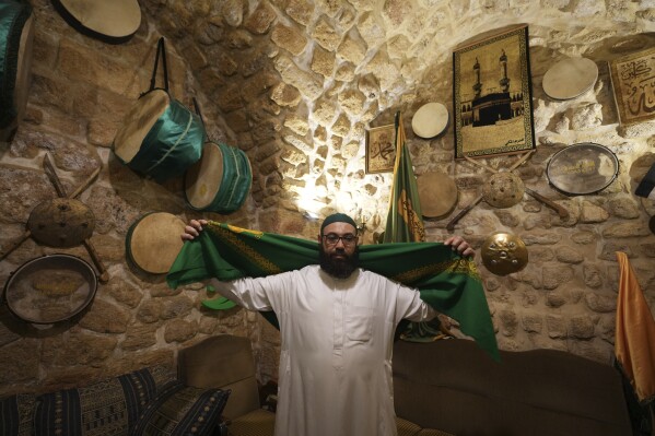 Mahmoud Fanas,a "musaharati,"or "dawn caller," who beats on a drum to wake up Muslims for a meal before sunrise during Ramadan, prepares his costumes inside his house in the southern Lebanese port city of Sidon, Lebanon, Sunday, March 16, 2025. (AP Photo/Hassan Ammar)