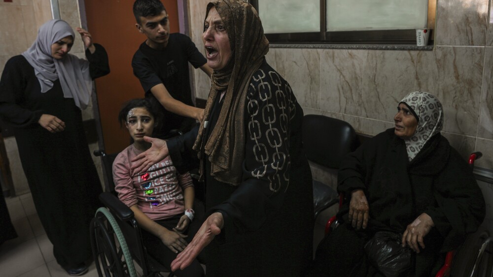 At al-Aqsa hospital in Deir el-Balah, central Gaza Strip, a Palestinian woman reacts next to the wounded during an Israeli airstrike, Sunday, Oct. 15, 2023. (AP Photo/Adel Hana)