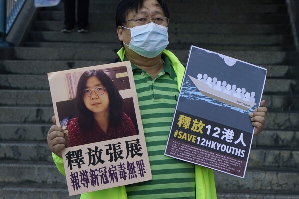 FILE - A pro-democracy activist holds placards with the picture of Chinese citizen journalist Zhang Zhan outside the Chinese central government's liaison office, in Hong Kong, Monday, Dec. 28, 2020. The whereabouts of Zhan, who served four years in prison for reporting on the early days of the pandemic in Wuhan and was expected to be released Monday, May 13, 2024, are unknown, raising concern from activists. Zhan, who had been sentenced to four years in prison on charges of “picking quarrels and provoking trouble,” a vaguely defined charge often used in political cases, has finished serving her sentence at Shanghai's Women Prison. (AP Photo/Kin Cheung, File)