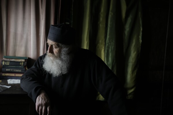 O monge cristão ortodoxo Padre Spyridon de Amorgos, olha da capela do Mosteiro de Panagia Hozoviotissa, na ilha de Amorgos, Grécia, domingo, 30 de março de 2025. (AP Photo/Petros Giannakouris)
