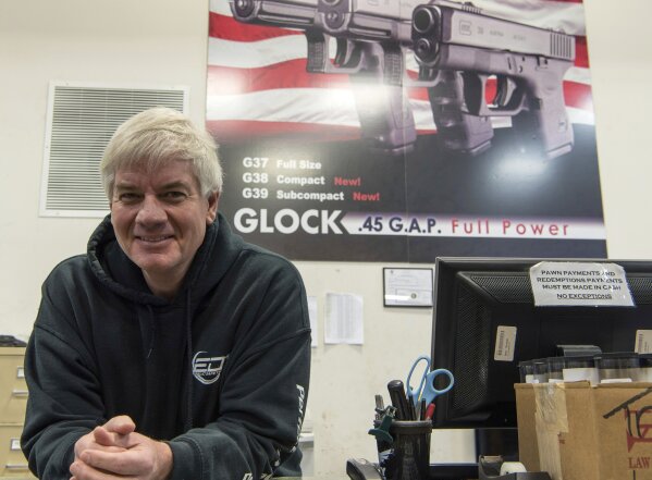 FILE - In this Jan. 31, 2017 file photo Ed Turner, owner of Ed's Public Safety gun shop in Stockbridge, Ga., poses for a portrait.  Americans' views are starkly different, underscoring the ever-widening divide over gun rights. Some call these gun-toting civilians patriots seeking to bring law and order in these turbulent times while others view them as vigilantes. Turner, a former police officer from metro Atlanta who now owns gun shops in Georgia, said he cringes seeing people openly carrying firearms. If someone is truly worried about their own safety, he said, concealing the weapon is “a much better approach than walking around like John Wayne.” (AP Photo/Lisa Marie Pane, File)