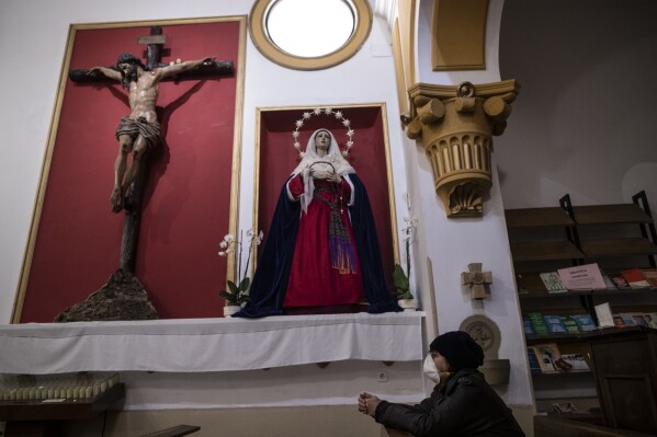 FILE - A woman prays at the San Ramon Nonato church after an Easter Holy Week procession was cancelled due to the coronavirus outbreak in Madrid, Spain, Thursday, April 9, 2020. Spain has approved a plan aimed at making reparation and economic compensation for victims of sex abuses committed by people connected to the Catholic Church. (AP Photo/Manu Fernandez, File)