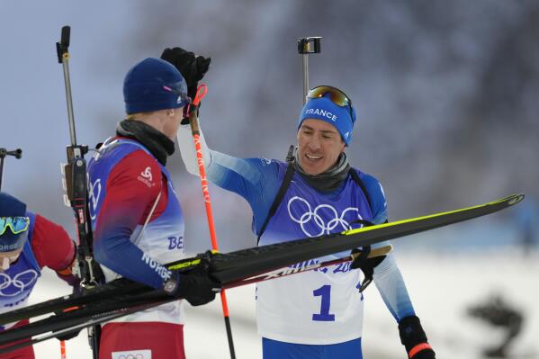 Quentin Fillon Maillet of France (1) greets Johannes Thingnes Boe of Norway after the men's 15-kilometer mass start biathlon at the 2022 Winter Olympics, Friday, Feb. 18, 2022, in Zhangjiakou, China. (AP Photo/Kirsty Wigglesworth)