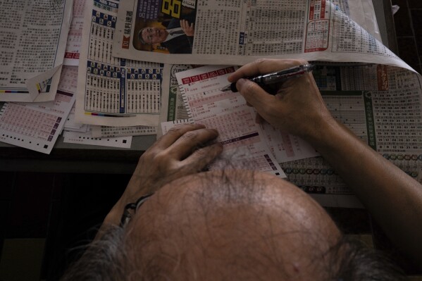 A visitor fills in betting slips at the Macao Jockey Club in Macao, Saturday, March 30, 2024. After more than 40 years, Macao’s horse racing track hosted its final races on Saturday, bringing an end to the sport in the city famous for its massive casinos. (AP Photo/Louise Delmotte)