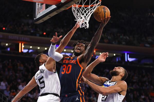 New York Knicks forward Julius Randle (30) drives to the basket against Minnesota Timberwolves forward Kyle Anderson (5) and center Rudy Gobert (27) during the second half of an NBA basketball game, Monday, March 20, 2023, in New York. (AP Photo/Noah K. Murray)