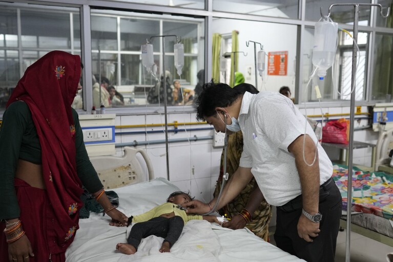 A doctor checks a boy suffering from heat related ailments at the Lalitpur district hospital, in Indian state of Uttar Pradesh, Saturday, June 17, 2023. Extreme heat is fast becoming a serious public health crisis in India. (AP Photo/Rajesh Kumar Singh)