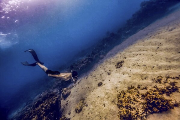 Chinese Wanxiong Huang, a free diving instructor, practices his skills in the sea around Bohol Island in the Philippines, April 16, 2023. A growing number of young Chinese are moving overseas, frequently to Southeast Asia, to escape their homeland's ultra-competitive work culture, limited opportunities and family pressures. There is no exact data on the number of the moves, the popular Chinese social media platform Xiaohongshu, hundreds of people have discussed relocating to Thailand. (AP Photo/Shaoxu Wang)