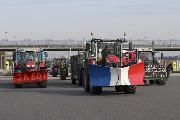 Farmers drive their tractors a highway leading to Paris, Monday, Jan. 29, 2024 near Chamant, north of Paris. Protesting farmers vowed to encircle Paris with tractor barricades and drive-slows on Monday, aiming to lay siege to France's seat of power in a battle with the government over the future of their industry, which has been shaken by repercussions of the Ukraine war. (AP Photo/Matthieu Mirville)