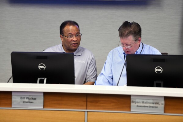 Bill Walker, Chairman of the Little Rock Municipal Airport Commission, left, and Bryan Malinowski, Executive Director of the Clinton National Airport, listen to a report by an airport director during a meeting of the commission on Tuesday, Feb. 27, 2024 in Little Rock, Ark. Bryan Malinowski, the executive director of Little Rock's airport who was injured earlier this week in a shootout with federal agents serving a search warrant at his home has died on Thuresday, March 21, 2024.(Stephen Swofford/Arkansas Democrat-Gazette via AP)