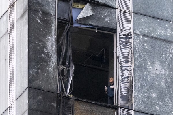 An investigator examines a damaged skyscraper in Moscow City business district after a reported drone attack in Moscow, Russia, Wednesday, Aug. 23, 2023. Russia's defense ministry and Moscow's mayor said Ukrainian drones were downed in Moscow and the region around the capital early Wednesday. No casualties were reported. (AP Photo)