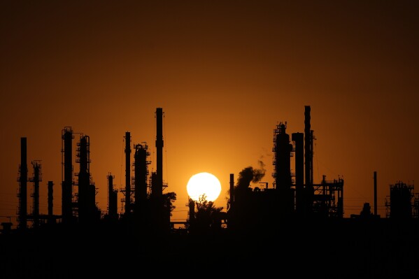 The CHS oil refinery is silhouetted against the setting sun Sept. 28, 2024, in McPherson, Kan. (AP Photo/Charlie Riedel, File)