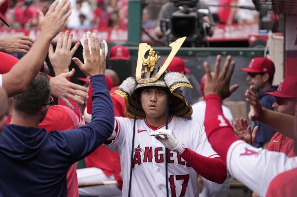 Los Angeles Angels' Shohei Ohtani is congratulated by teammates in the dugout after hitting a solo home run during the first inning of a baseball game against the Pittsburgh Pirates, Sunday, July 23, 2023, in Anaheim, Calif. (AP Photo/Mark J. Terrill)