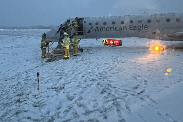 Greater Rochester International Airport firefighters assist passengers off an American Airlines plane that slid off a snowy taxiway after a flight from Philadelphia, Thursday, Thursday, Jan. 18, 2024, in Rochester, N.Y. (Vicky Ferguson via AP)