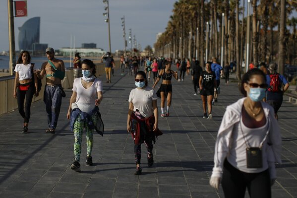 People walk along a seafront promenade in Barcelona, Spain, Saturday, May 2, 2020. Spaniards have filled the streets of the country to do exercise for the first time after seven weeks of confinement in their homes to fight the coronavirus pandemic. People ran, walked, or rode bicycles under a brilliant sunny sky in Barcelona on Saturday, where many flocked to the maritime promenade to get as close as possible to the still off-limits beach. (AP Photo/Emilio Morenatti)