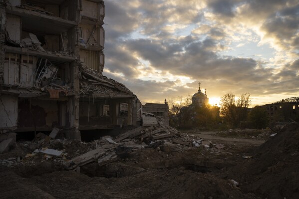 The sun sets over a destroyed building in Izyum, Ukraine, Tuesday, Oct. 24, 2023. (AP Photo/Bram Janssen)