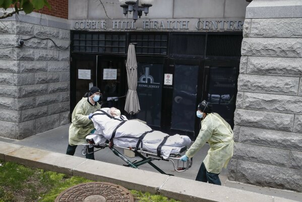 FILE - In this Friday, April 17, 2020 file photo, a patient is wheeled out of the Cobble Hill Health Center by emergency medical workers in the Brooklyn borough of New York. The facility has listed dozens of deaths linked to the COVID-19 coronavirus pandemic. In New York state, the nation’s leader in nursing home deaths, the Greater New York Hospital Association lobbying group wrote the first draft of an emergency declaration making it the only state with protection from both civil lawsuits and criminal prosecution arising from the pandemic, with the order signed by Democratic Gov. Andrew Cuomo. (AP Photo/John Minchillo)