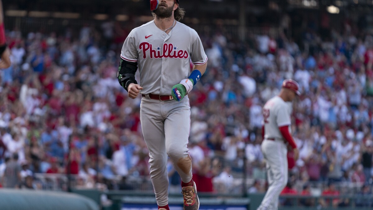 Philadelphia Phillies' Bryce Harper (3) high fives Trea Turner, right,  after scoring on an RBI-single hit by Bryson Stott during the third inning  of a baseball game against the Los Angeles Dodgers