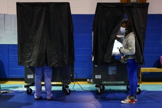 A voter looks from a booth while casting their ballot on election day in Philadelphia, Tuesday, Nov. 7, 2023. Social media users are misrepresenting an issue with voting machines in Pennsylvania's Northampton County, falsely claiming that they were rigged to flip votes. (AP Photo/Matt Rourke)