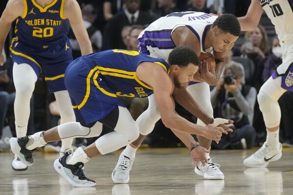 Sacramento Kings forward Keegan Murray, right, grabs the ball next to Golden State Warriors guard Stephen Curry during the first half of an NBA basketball game in San Francisco, Wednesday, Nov. 1, 2023. (AP Photo/Jeff Chiu)