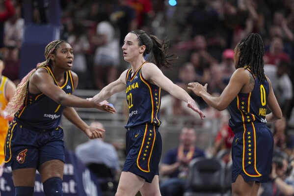 Indiana Fever guard Caitlin Clark (22) is congratulated by Aliyah Boston (7) and Kelsey Mitchell (0) during the second half of the team's WNBA basketball game against the Los Angeles Sparks in Indianapolis, Tuesday, May 28, 2024. (AP Photo/Michael Conroy)
