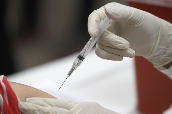 FILE - In this Thursday, Jan. 23, 2020 file photo, a patient receives an influenza vaccine in Mesquite, Texas. On Wednesday, Aug. 19, 2020, Alex Azar, the head of the U.S. Department of Health and Human Services, announced that pharmacists in all 50 states will be authorized to give childhood vaccinations this fall, due to a federal order that will temporarily preempt pharmacy restrictions in 22 states. (AP Photo/LM Otero)