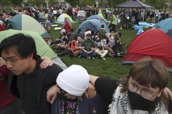 Pro-Palestinian protesters link arms around campers as police show up to their encampment on Washington University's campus, Saturday, April 27, 2024, in St. Louis, Mo. Dozens were arrested during the protest. (Christine Tannous/St. Louis Post-Dispatch via AP)