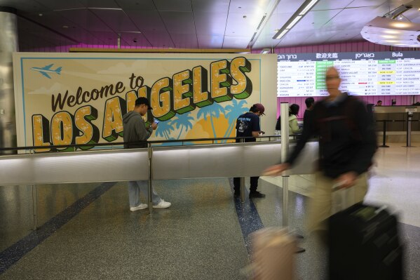 A traveler carts their luggage through the international arrivals area at the Los Angeles International Airport in Los Angeles, Saturday, June 8, 2025. (AP Photo/William Liang)