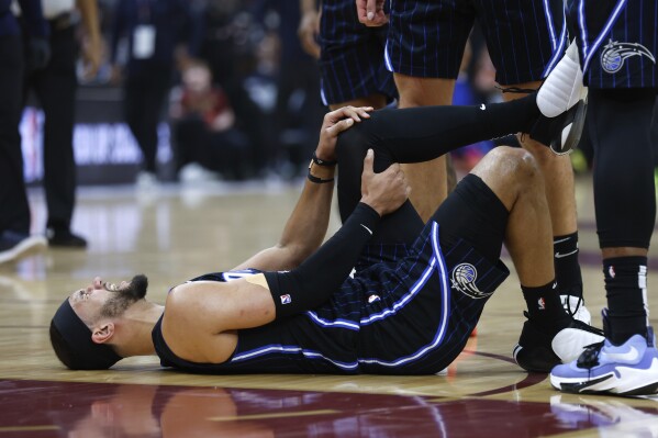 Orlando Magic guard Jalen Suggs holds his knee after being injured during the first half of Game 2 of an NBA basketball first-round playoff series against the Cleveland Cavaliers, Monday, April 22, 2024, in Cleveland. (AP Photo/Ron Schwane)